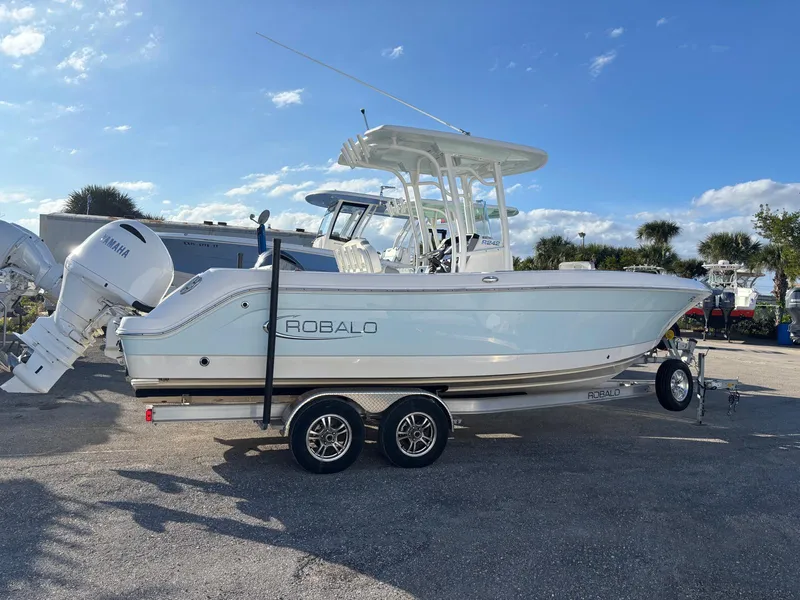 Slide: The Image of 2022 Robalo R242 boat on trailer with Yamaha engine, parked outdoors under blue sky. - 1