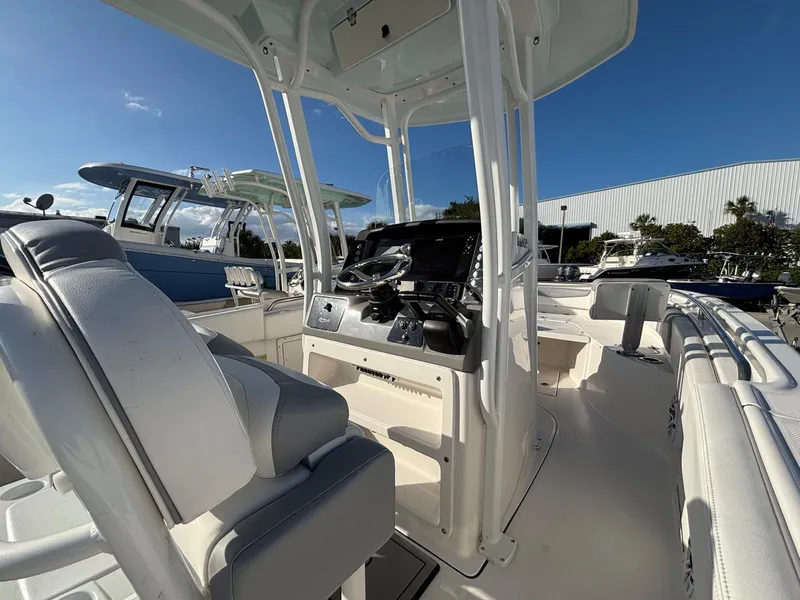 Slide: The Image of 2022 Robalo R242 boat interior with helm, seating, and clear blue sky background. - 13