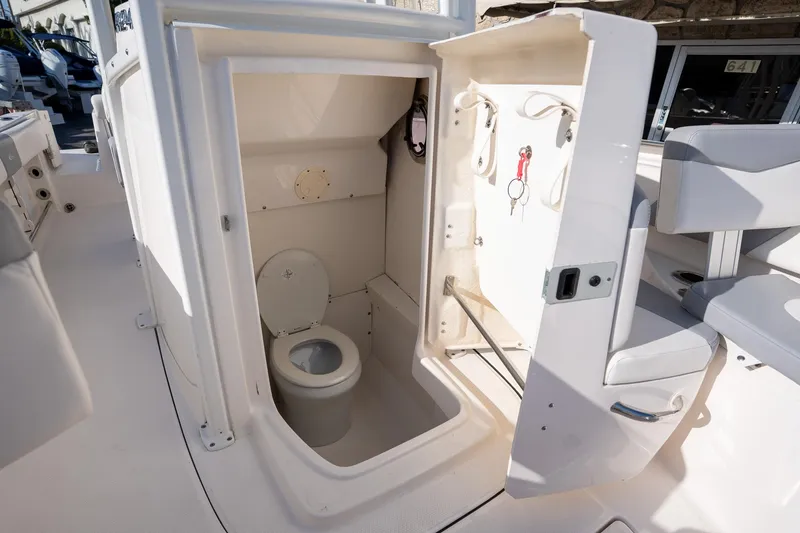 Slide: The Image of 2022 Robalo R242 boat interior with compact marine toilet and storage area. - 30