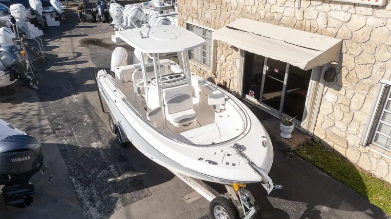 Slide: The Image of 2022 Robalo R242 boat on trailer outside a stone building, surrounded by other boats. - 5