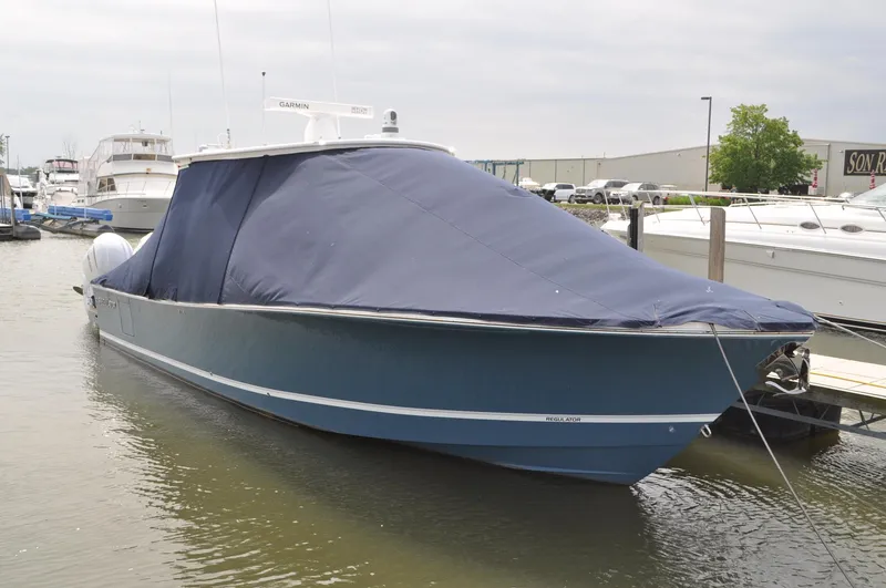 Slide: The Image of 2023 Regulator 34 boat with blue cover docked in marina. - 0