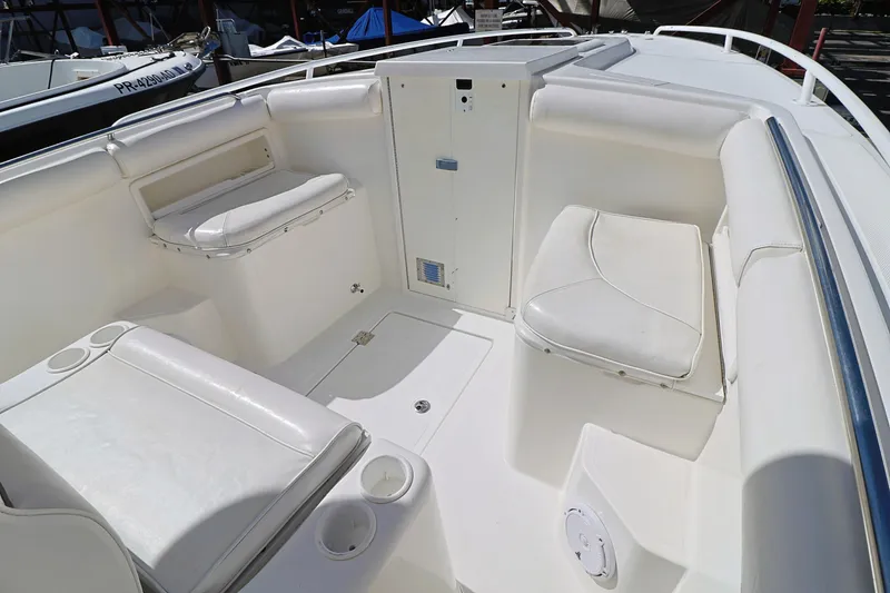 Slide: The Image of 2004 Marlago 35 Sport Cuddy boat interior with white seating and storage compartments. - 15