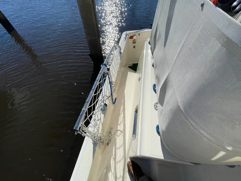 Slide: The Image of 2005 Mainship 430 Aft Cabin Trawler deck with safety netting and water reflection. - 15