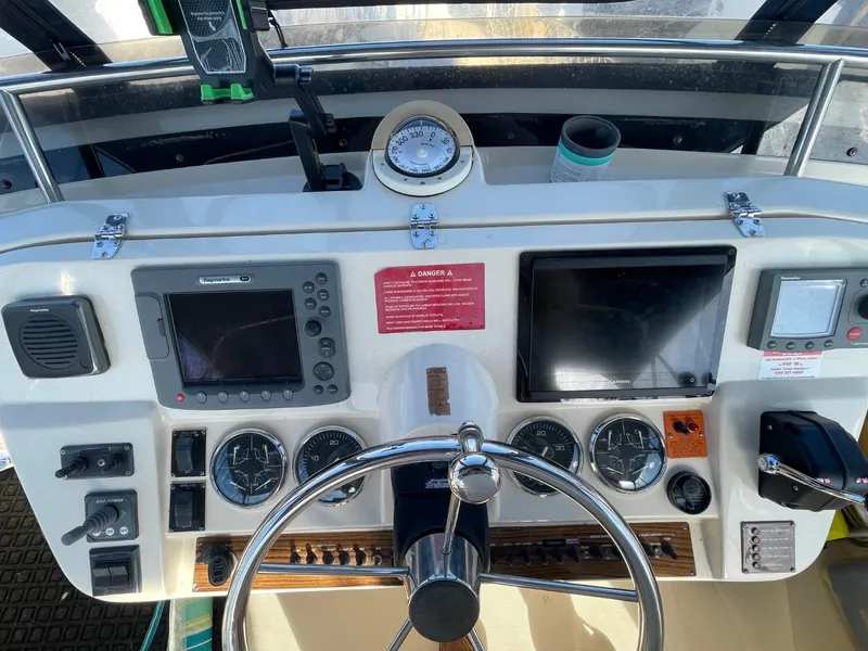 Slide: The Image of 2005 Mainship 430 Aft Cabin Trawler helm with navigation instruments and steering wheel. - 19