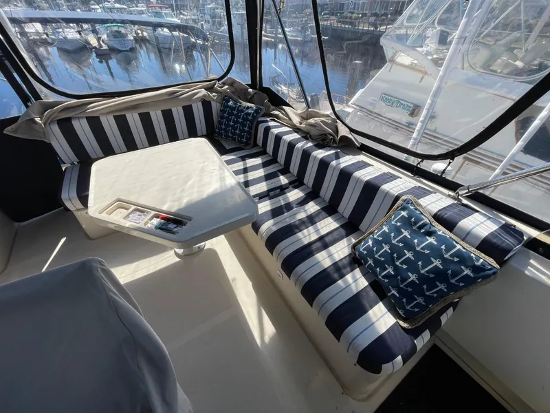 Slide: The Image of 2005 Mainship 430 Aft Cabin Trawler interior with striped seating and nautical-themed cushions. - 26