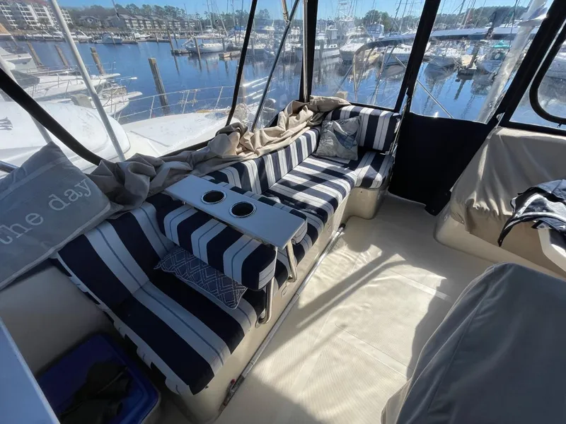 Slide: The Image of 2005 Mainship 430 Aft Cabin Trawler interior with striped seating, marina view. - 28