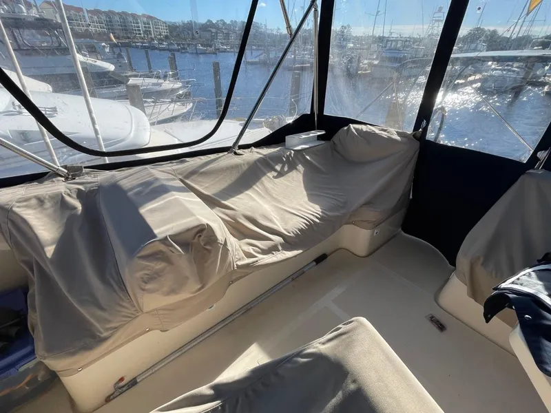 Slide: The Image of 2005 Mainship 430 Aft Cabin Trawler interior with covered seating and marina view. - 31