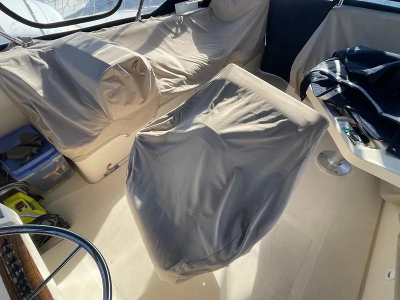 Slide: The Image of 2005 Mainship 430 Aft Cabin Trawler interior with covered seating and steering wheel. - 32