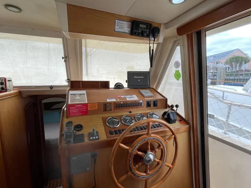 Slide: The Image of 2005 Mainship 430 Aft Cabin Trawler helm with wooden steering wheel and navigation instruments. - 34