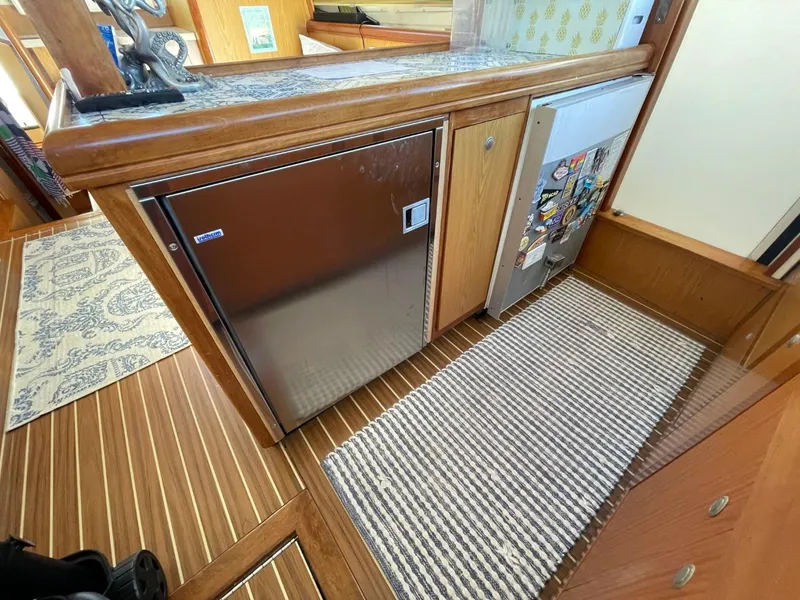 Slide: The Image of 2005 Mainship 430 Aft Cabin Trawler interior with wood flooring and compact kitchen appliances. - 38