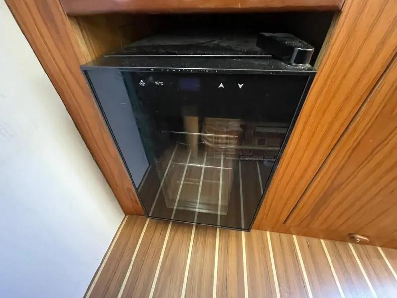 Slide: The Image of Mini fridge in 2005 Mainship 430 Aft Cabin Trawler, wooden interior, glass door. - 42