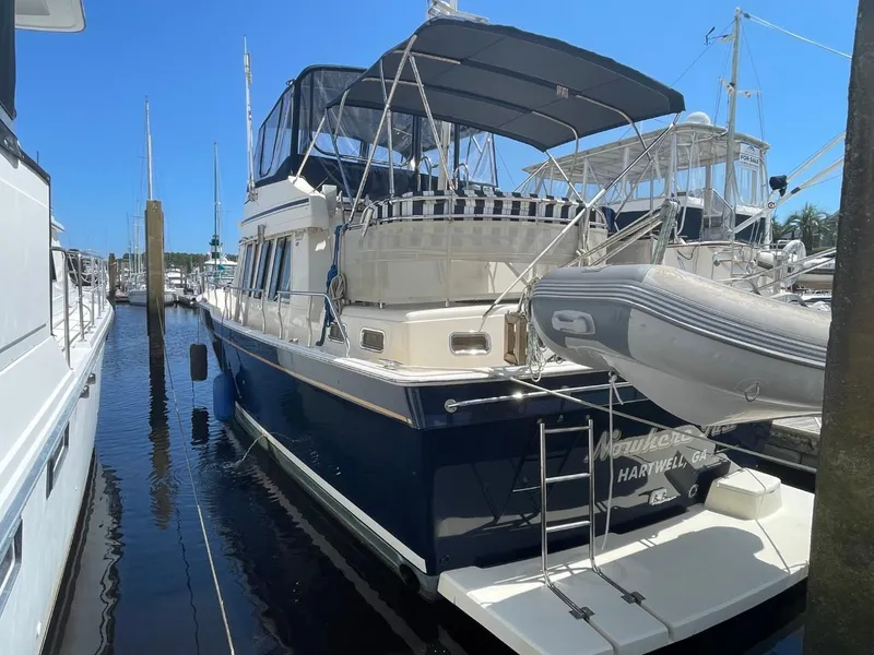 Slide: The Image of 2005 Mainship 430 Aft Cabin Trawler docked, featuring blue hull and covered deck. - 5