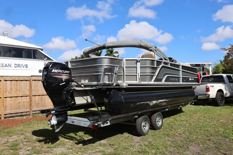 Slide: The Image of 2017 Ranger Reata 200F pontoon boat on trailer, parked outdoors under blue sky. - 14