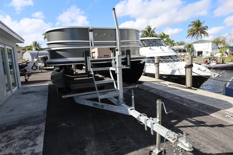 Slide: The Image of 2017 Ranger Reata 200F pontoon boat on trailer, dockside with palm trees and blue sky. - 15