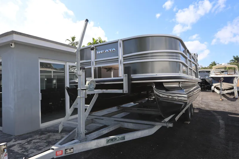 Slide: The Image of 2017 Ranger Reata 200F pontoon boat on trailer, parked outdoors under blue sky. - 16