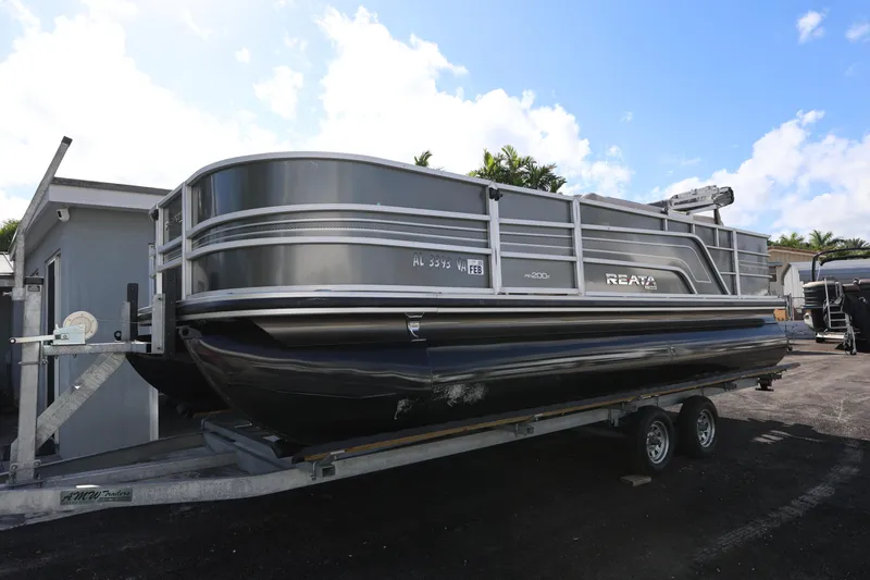 Slide: The Image of 2017 Ranger Reata 200F pontoon boat on trailer, parked outdoors under blue sky. - 17