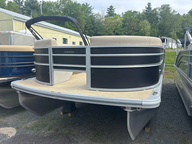 The Image of 2025 Harris Cruiser 230 pontoon boat with sleek black exterior, docked outdoors. - 0