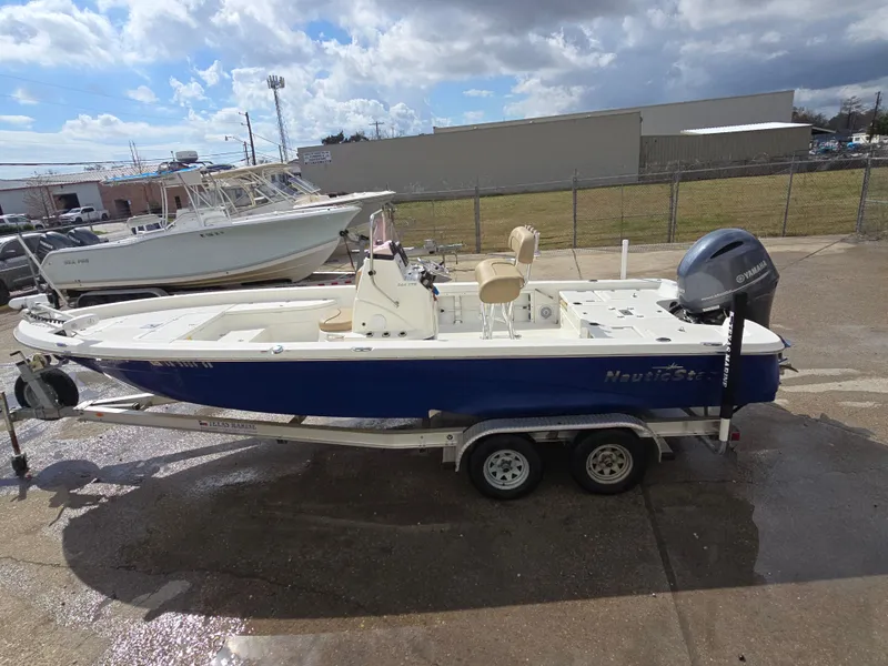 Slide: The Image of 2019 NauticStar 244 XTS boat on trailer, blue and white design, parked outdoors. - 14