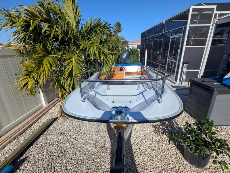 Slide: The Image of 1987 Boston Whaler 150 Super Sport boat on gravel, surrounded by plants and a screened enclosure. - 3