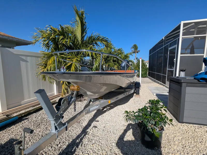 Slide: The Image of 1987 Boston Whaler 150 Super Sport boat on trailer, surrounded by tropical plants. - 4