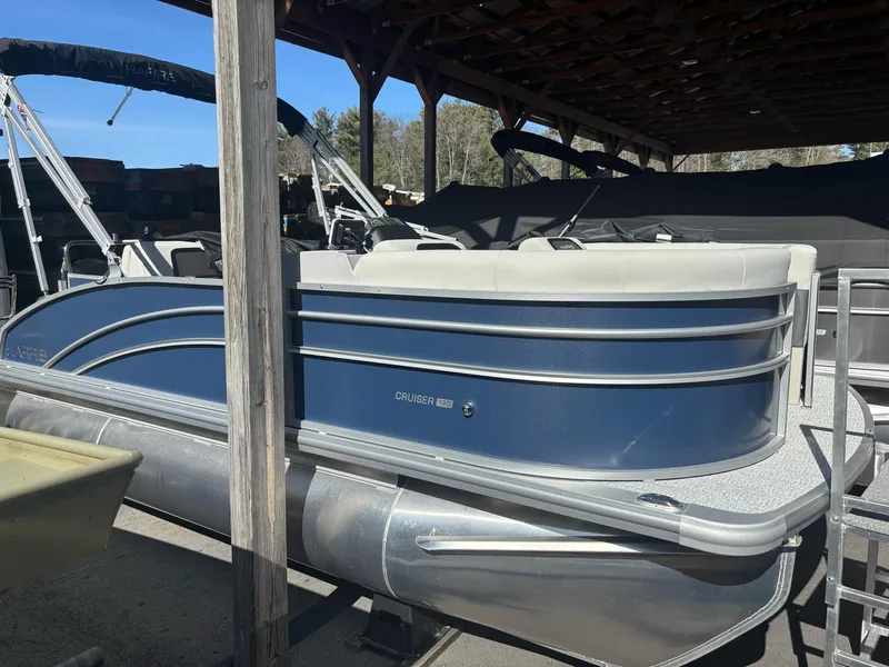 Slide: The Image of 2025 Harris Cruiser 190 pontoon boat under a wooden shelter. - 0