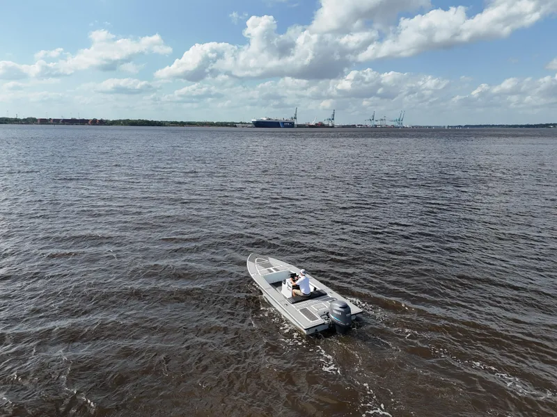 Slide: The Image of 1996 Hewes 18 Redfisher boat on open water under a partly cloudy sky. - 11