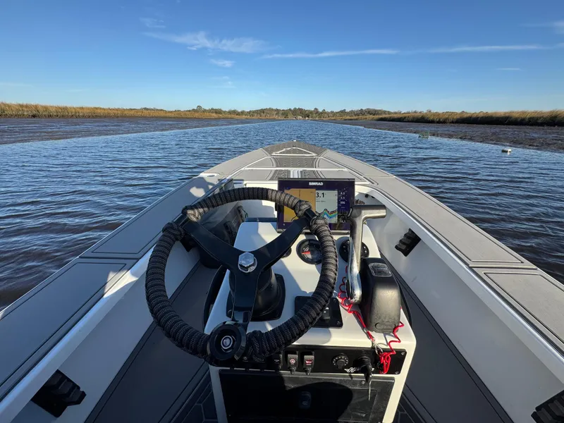 Slide: The Image of 1996 Hewes 18 Redfisher boat on calm water, featuring steering wheel and control panel. - 13
