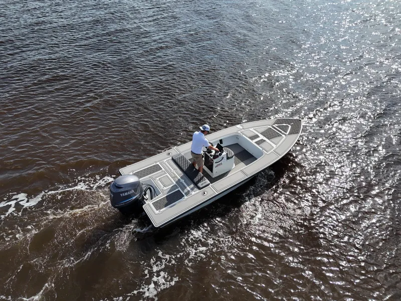Slide: The Image of 1996 Hewes 18 Redfisher boat on water, aerial view, with person steering. - 2