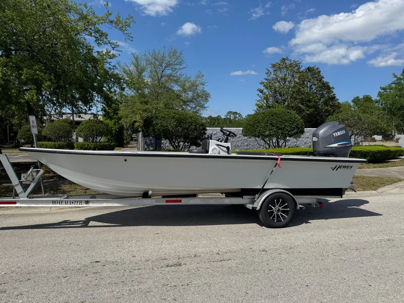 Slide: The Image of 1996 Hewes 18 Redfisher boat on trailer, parked outdoors under a clear blue sky. - 27