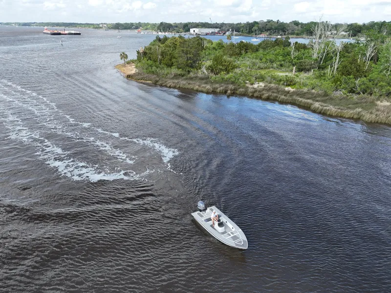 Slide: The Image of Aerial view of 1996 Hewes 18 Redfisher boat navigating a scenic river. - 6