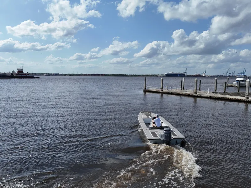 Slide: The Image of 1996 Hewes 18 Redfisher boat cruising on a sunny day near a dock. - 8