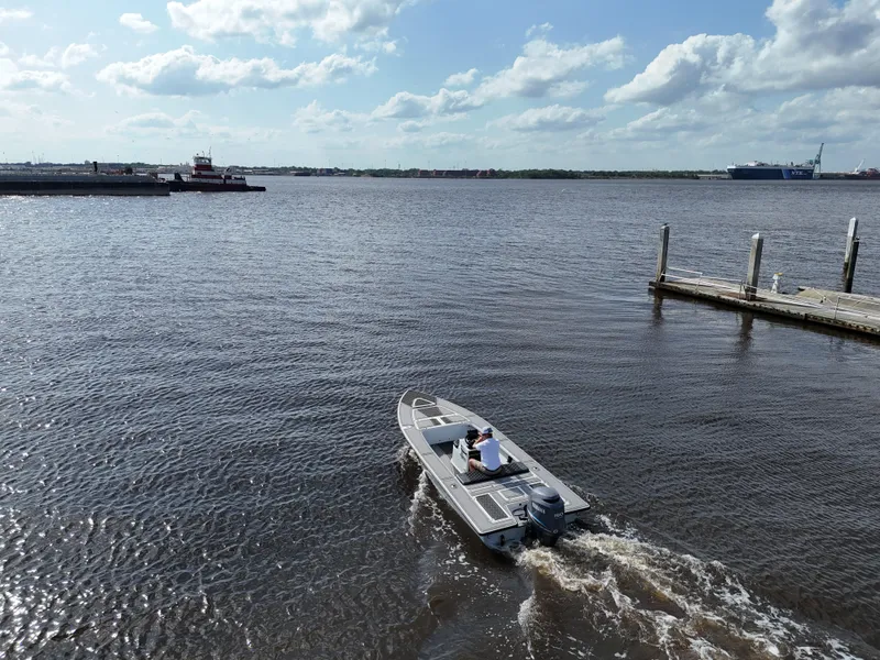 Slide: The Image of 1996 Hewes 18 Redfisher boat cruising on a calm river near a dock. - 9