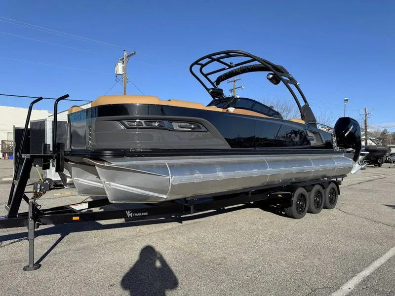 Slide: The Image of 2025 Avalon 2585 27-3 Excalibur LTD QL pontoon boat on trailer, parked outdoors. - 2