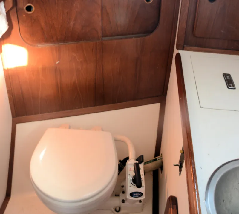Slide: The Image of 1982 Morgan 32 yacht bathroom with toilet and sink, featuring wooden cabinetry. - 13