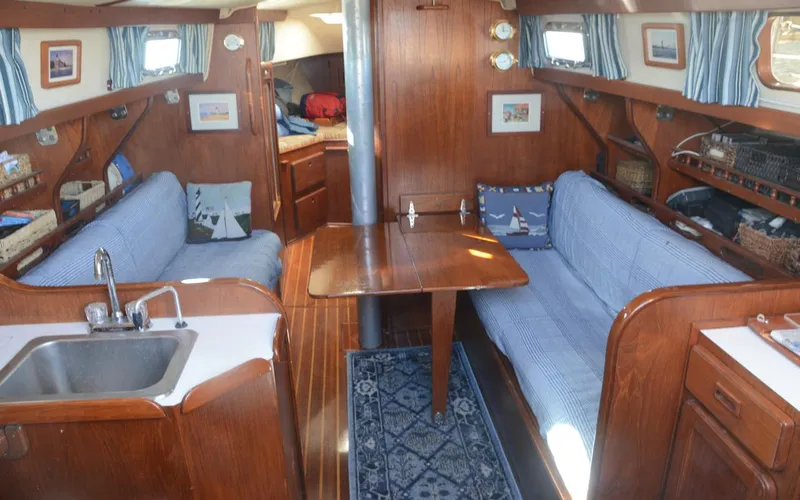 Slide: The Image of 1982 Morgan 32 yacht interior with wooden finish, blue upholstery, and compact kitchen area. - 14