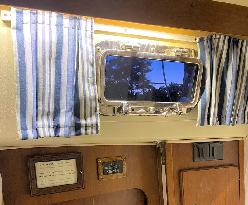 Slide: The Image of Interior of a 1982 Morgan 32 sailboat with striped curtains and a porthole window. - 30