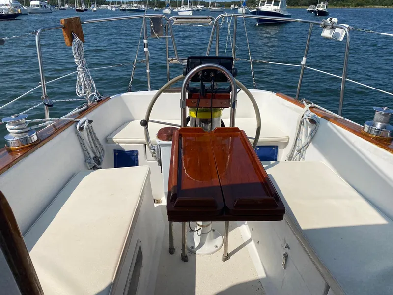 Slide: The Image of 1982 Morgan 32 sailboat cockpit with wooden table, steering wheel, and marina view. - 5