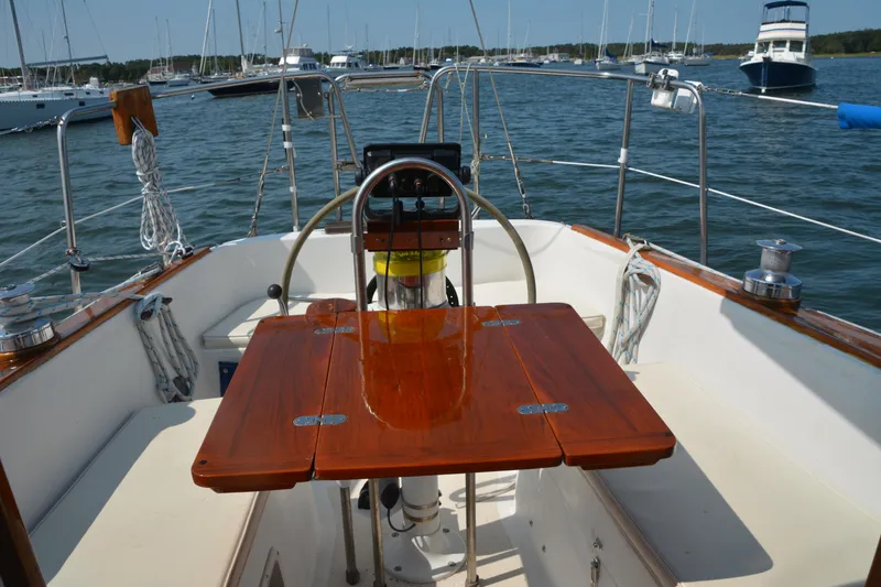 Slide: The Image of Cockpit of 1982 Morgan 32 sailboat with wooden table, steering wheel, and marina view. - 6