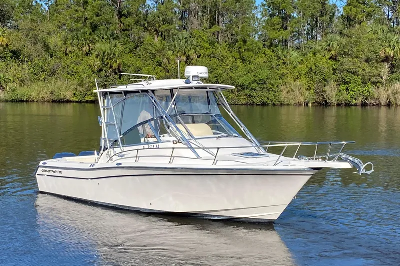 Slide: The Image of 2002 Grady-White Express 265 boat on calm water, surrounded by lush greenery. - 0