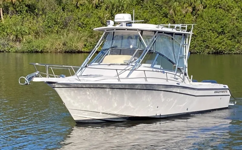 Slide: The Image of 2002 Grady-White Express 265 boat on calm water, surrounded by lush greenery. - 1