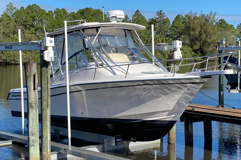 Slide: The Image of 2002 Grady-White Express 265 boat on lift, surrounded by trees and water. - 4