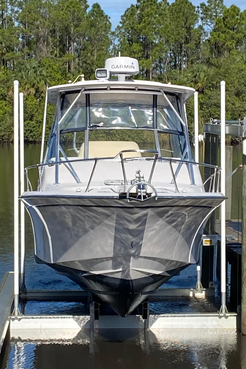 Slide: The Image of 2002 Grady-White Express 265 boat on lift, surrounded by trees and water. - 5