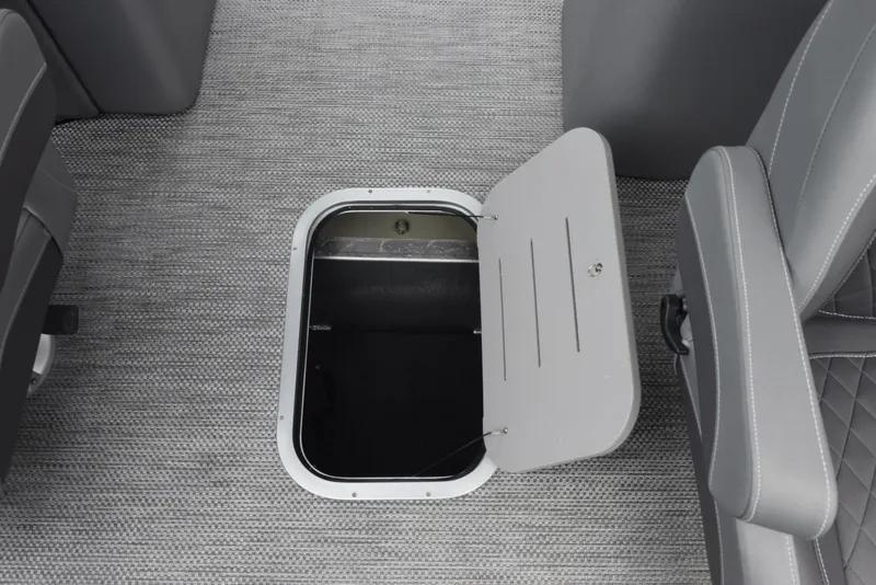 Slide: The Image of 2023 Bennington 23 LTFB boat storage compartment with open hatch on gray carpeted floor. - 16