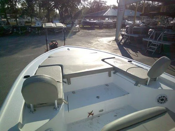 Slide: The Image of 2025 Sportsman 247 MASTERS boat interior with seating and storage in a sunny marina. - 7