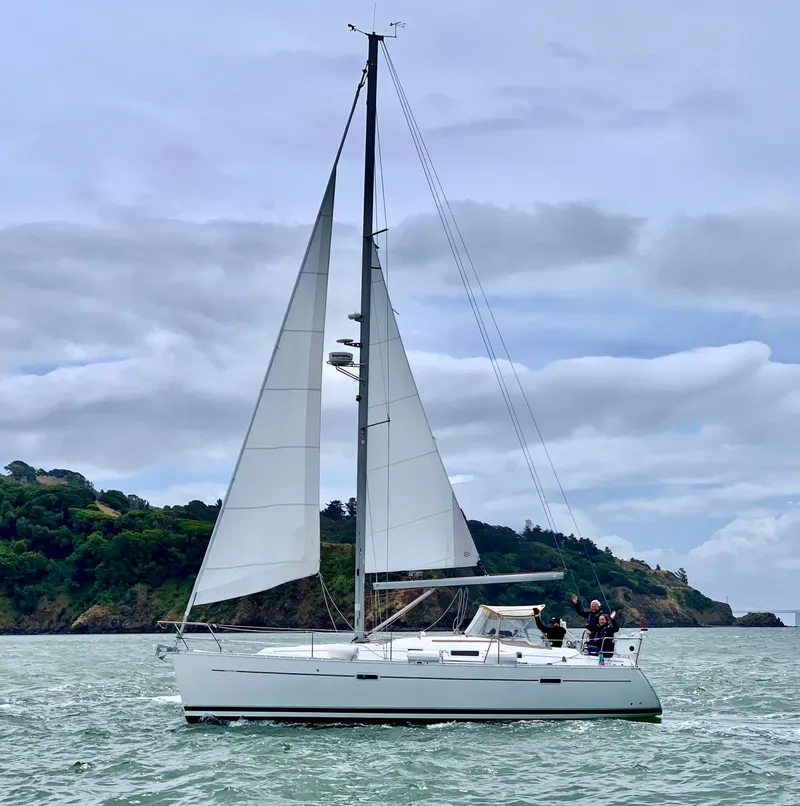 Slide: The Image of 2006 Beneteau Oceanis Clipper 343 sailing near lush coastline under cloudy skies. - 1