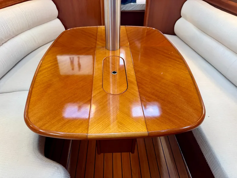 Slide: The Image of Interior of 2006 Beneteau Oceanis Clipper 343 with polished wooden table and cushioned seating. - 10