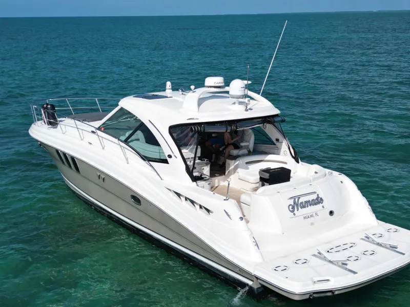 The Image of 2005 Sea Ray 48 Sundancer cruising on open water under a clear blue sky. - 0