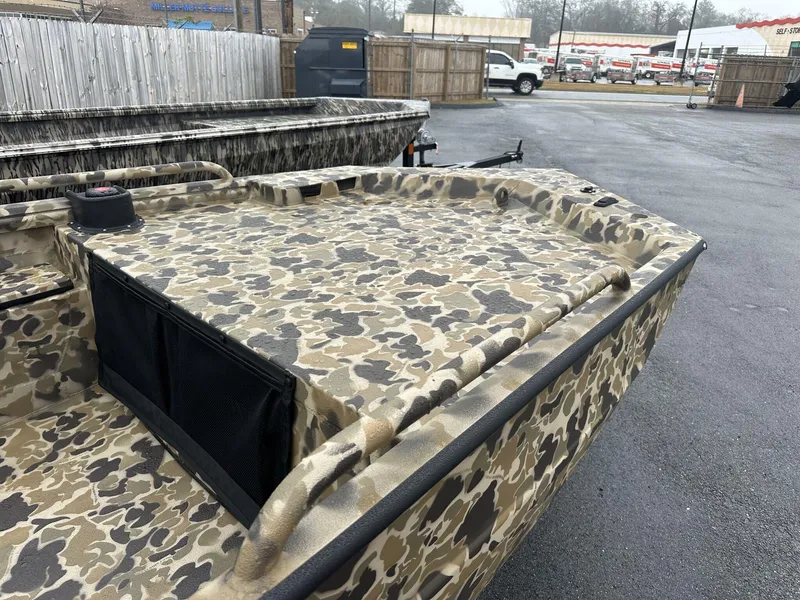 Slide: The Image of 2025 Excel Shallow Water F4 boat with camouflage paint, parked outdoors. - 4