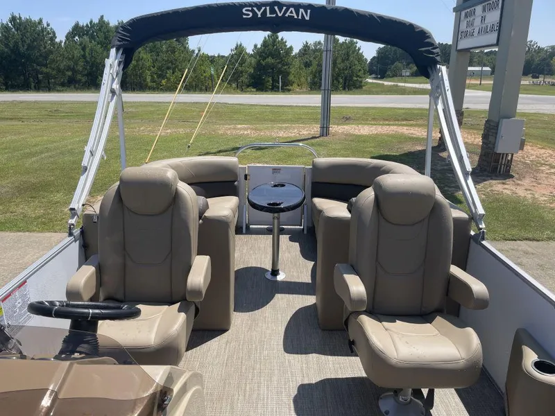 Slide: The Image of 2024 Sylvan 822 LZ Mirage pontoon boat interior with beige seating and table. - 6