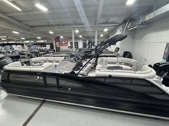 Slide: The Image of 2025 Bennington Q Quad Bench 25 QFB pontoon boat in showroom, featuring luxurious seating. - 6